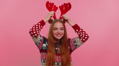 Noel geyiği boynuzlarıyla genç bir kız müzik dinliyor, disko dansı yapıyor, eğleniyor.