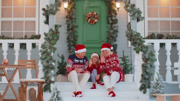 Ανώτερος παππούς γιαγιά με εγγονή κάθεται στη βεράντα του σπιτιού των Χριστουγέννων χαιρετώντας γεια — Αρχείο Βίντεο