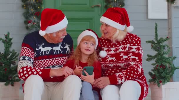 Mayores abuelos de la familia, nieta comprar regalos de Navidad en línea en el teléfono móvil, compras — Vídeos de Stock