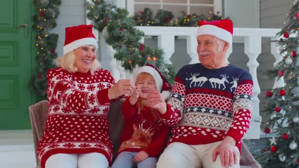 Senior famille couple grand-mère grand-père avec petite-fille tenant allumé Bengale lumières scintillant — Video
