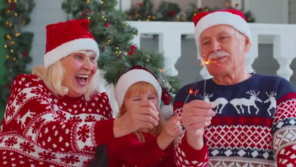 Szczęśliwy starszy para dziadkowie z wnuczka gospodarstwa oświetlone bengalskie Christmas lights sparklers — Wideo stockowe