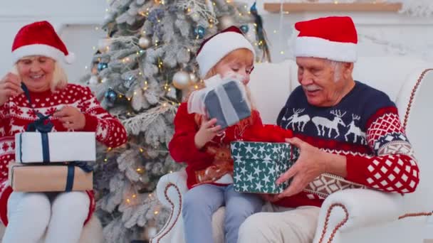 Wnuczka exhcanging prezent świąteczny pudełka z zdumiony szczęśliwy starszy dziadek w domu — Wideo stockowe