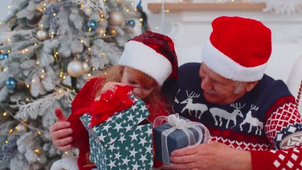 Grandchild girl kidexhcanging Christmas gift present boxes with happy elderly grandfather at home — Stock Video