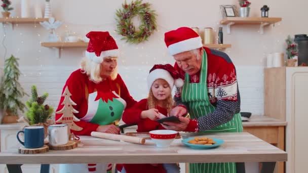 Oudere grootouders en kleinkind kijken kooklessen met digitale tablet in de kerstkeuken — Stockvideo