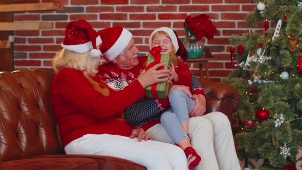 Grandfather, grandmother gifting Christmas present box to amazed happy grandchild girl kid at home — Stock Video