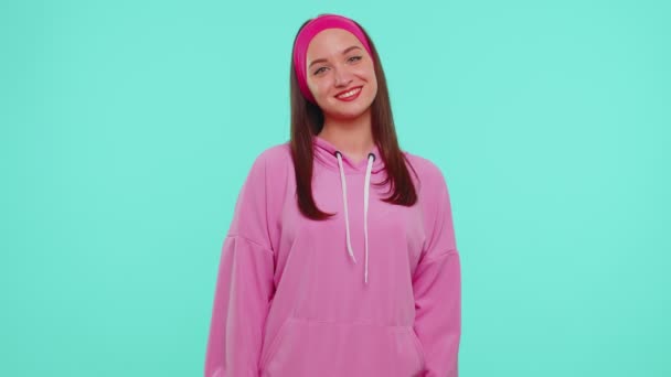 Весёлая милая студентка-модель в розовой толстовке улыбается и смотрит в камеру — стоковое видео