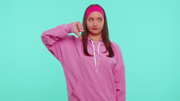 Menina perturbada com capuz rosa mostrando polegares para baixo sinal gesto, desaprovação, insatisfeito, desgosto — Vídeo de Stock