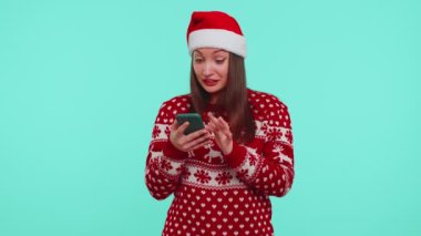 Kırmızı Noel süveteri giyen yetişkin bir kız. Akıllı telefon görüntüsü. İçten bir sevinç.