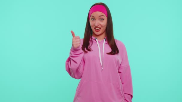 Teen stylisches Mädchen in rosa Kapuzenpulli zeigt Daumen hoch und nickt zustimmend, erfolgreiche gute Arbeit — Stockvideo