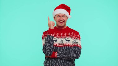 Kırmızı Noel süveteri giymiş heyecanlı bir adam parmağını kaldır ve yaratıcı bir plan yap.