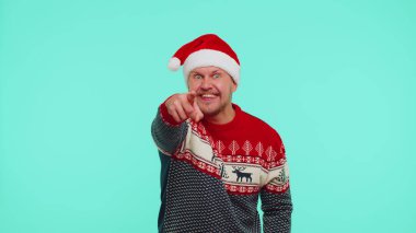 Kırmızı Noel kazaklı adam heyecanla gülümsüyor, kamerayı işaret ediyor, güzellik şanslı kazananı seçiyor.