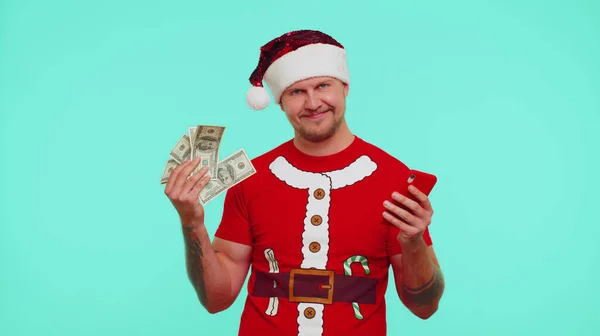 Homem em t-shirt de Natal olhando smartphone sinceramente regozijando-se ganhar sucesso sorte recebendo dinheiro — Fotografia de Stock