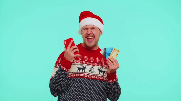 穿圣诞红毛衣的男人用手机，塑料信用卡，赢了，斑马，哇 — 图库照片
