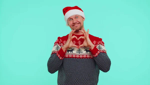 Homem sorridente em camisola de Natal faz gesto do coração demonstra sinal de amor expressa bons sentimentos — Fotografia de Stock