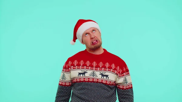 Божевільний чоловік в светрі Санта Різдвяний капелюх демонструє язик, обманюючи створення дурних облич — стокове фото