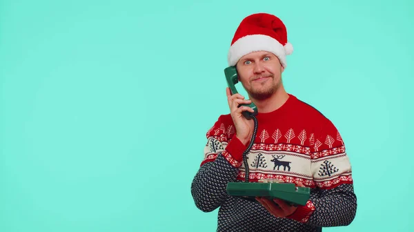 Забавный человек в рождественском свитере говорит по проволочному винтажному телефону 80-х годов, говорит: — стоковое фото