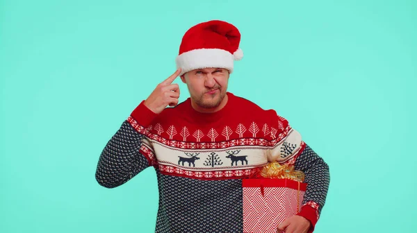 Людина в різдвяному светрі вказує на камеру, показуючи дурний жест, звинувачуючи якогось ідіота в плані — стокове фото
