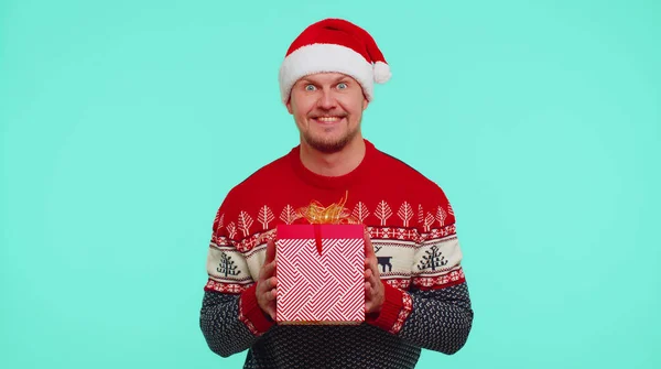 身穿圣诞老人毛衣、头戴圣诞礼品盒的快乐男人伸出手来对着摄像机 — 图库照片