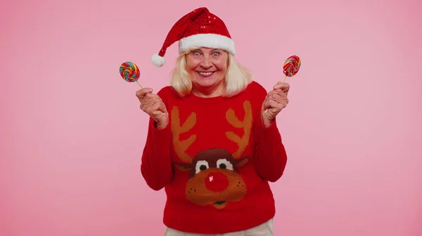 Бабушка в рождественском свитере с леденцами в полоску, прячущимися за ними. — стоковое фото