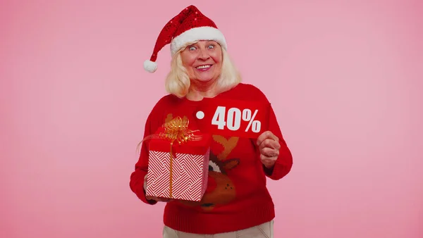 Бабушка в рождественском свитере с подарочной коробкой и 40-процентной скидкой — стоковое фото