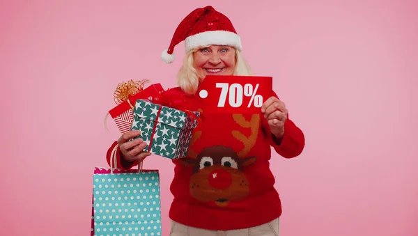 Зрелая женщина в рождественском свитере с подарочной коробкой и 70-процентной надписью на баннере — стоковое фото