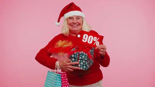 ギフトボックスと90パーセント割引碑文バナーテキストを示すクリスマスセーターのシニア女性 — ストック写真