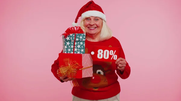 Бабушка в рождественском свитере с подарочной коробкой и 80-процентной скидкой — стоковое фото