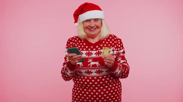 Пожилая женщина Рождество бабушка использовать мобильный телефон, пластиковые кредитные карты выиграть calebrate ничего себе — стоковое фото