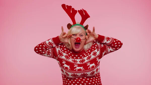 Старша Різдвяна бабуся з оленячими рогами слухає музику, танцює диско, обманює навколо — стокове фото
