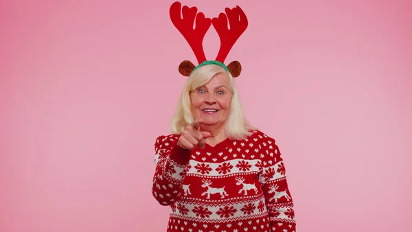 Старша Різдвяна бабуся посміхається з ентузіазмом вказуючи на красу камери, вибираючи щасливого переможця — стокове фото