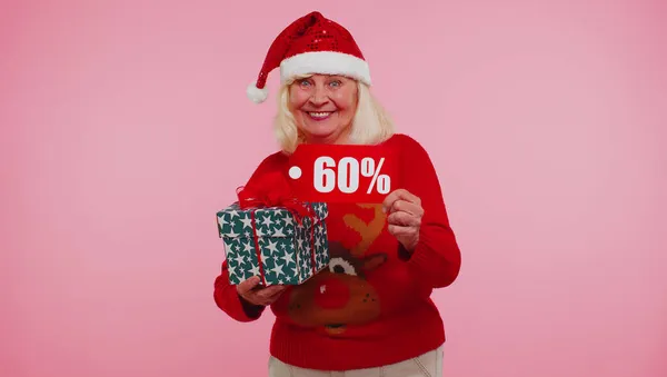 Бабушка в рождественском свитере с подарочной коробкой и 60-процентной надписью — стоковое фото