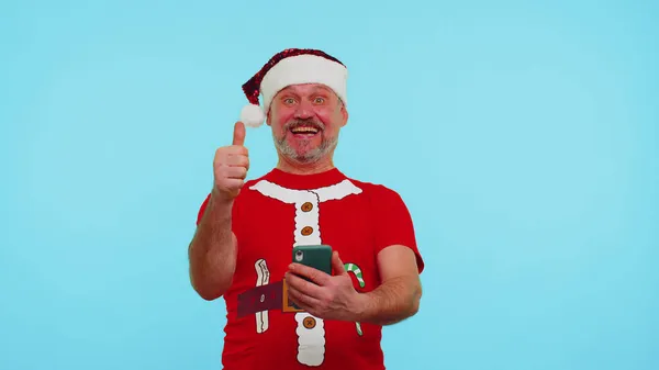 Mann im modischen Weihnachts-T-Shirt auf Smartphone-Display freut sich aufrichtig über Erfolg — Stockfoto