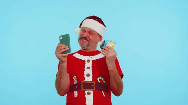 Mann im weihnachtsroten T-Shirt benutzt Handy, Plastikkreditkarten, gewinnt, kalebriert, wow — Stockfoto