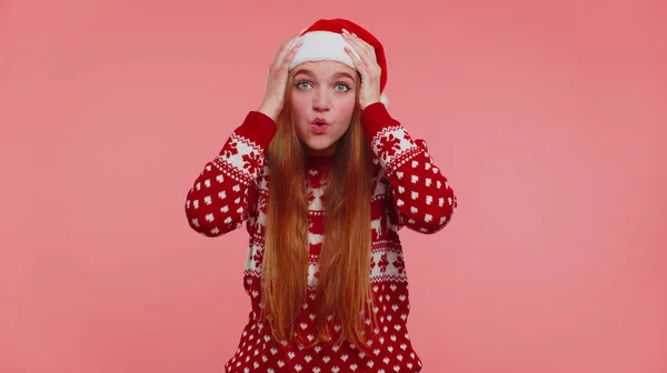 Adolescente ragazza adulta in cappello di Natale alzando le mani a sorpresa scioccato da improvvisa vittoria, wow emozione — Foto Stock