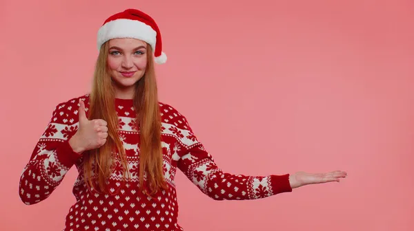 Mulher usa veado vermelho ano novo suéter mostrando polegares para cima e apontando para no espaço de publicidade em branco — Fotografia de Stock
