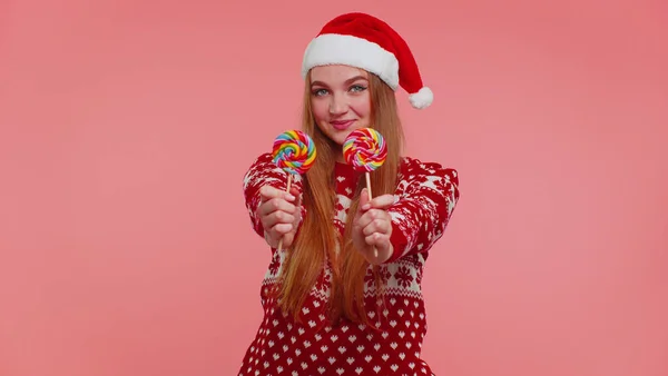 Joyeuse fille en pull de Noël rouge, chapeau présentant des sucettes rayées de bonbons, étire les mains — Photo