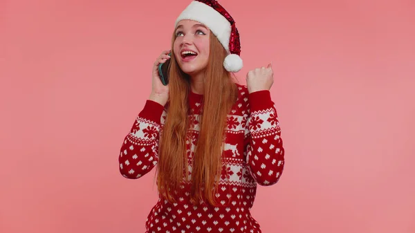 Дівчина в Різдвяний светр робить мобільний телефонний дзвінок, відправляючи побажання привітати родину друзів — стокове фото