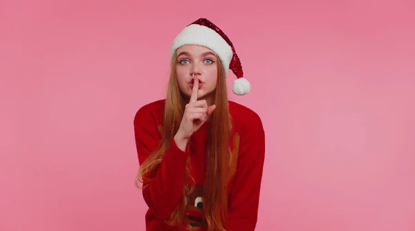 Mulher usa camisola de Natal vermelho pressiona dedo indicador para os lábios faz sinal de gesto silêncio, segredo — Fotografia de Stock