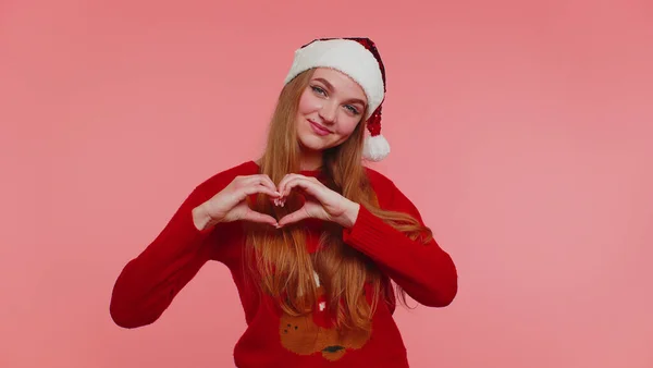 Sourire fille en pull de Noël fait geste de coeur démontre signe d'amour exprime de bons sentiments — Photo