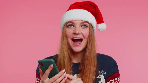 Donna in elegante maglione di Natale cercando display smartphone sinceramente gioire vincere fortuna successo — Foto Stock