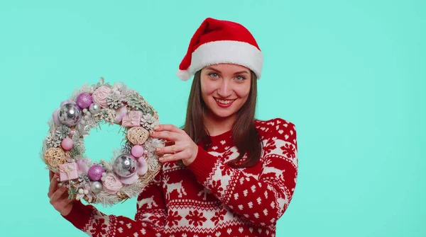 Adulte fille souriante en rouge chandail de Noël tenir lever le doigt sur jouet couronne festive — Photo