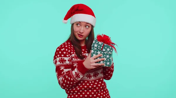 Menina engraçada usa chifres de veado de camisola de Ano Novo recebido presente, interessado em que dentro da caixa de presente — Fotografia de Stock