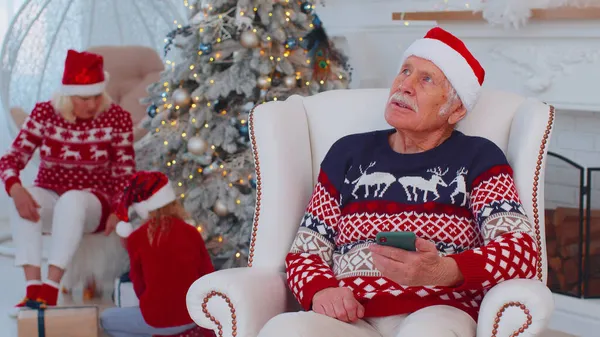 Starszy dziadek człowiek kupić prezenty świąteczne robi zakupy online na smartfonie w domu — Zdjęcie stockowe