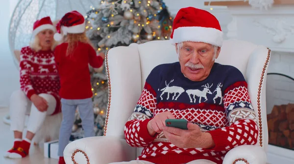 Starszy dziadek człowiek kupić prezenty świąteczne robi zakupy online na telefon komórkowy w domu — Zdjęcie stockowe
