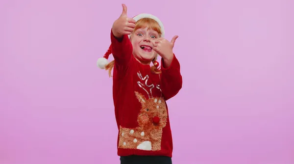 Menina engraçada em camisola de Ano Novo vermelho levanta os polegares concorda com algo bom, como, fundo violeta — Fotografia de Stock