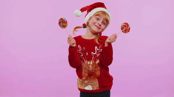 Радісна дівчина в різдвяному светрі, капелюх тримає цукерки смугасті льодяники, танцює, робить дурні обличчя — стокове фото