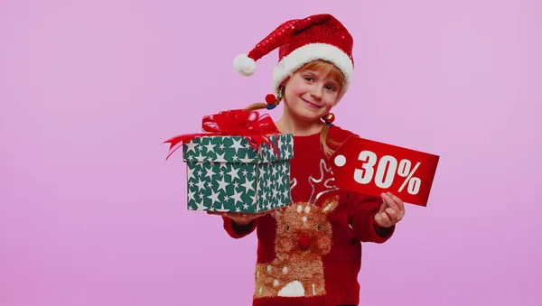 Menina criança em chapéu de Natal mostrando caixas de presente e 30 por cento de desconto inscrições banner texto — Fotografia de Stock