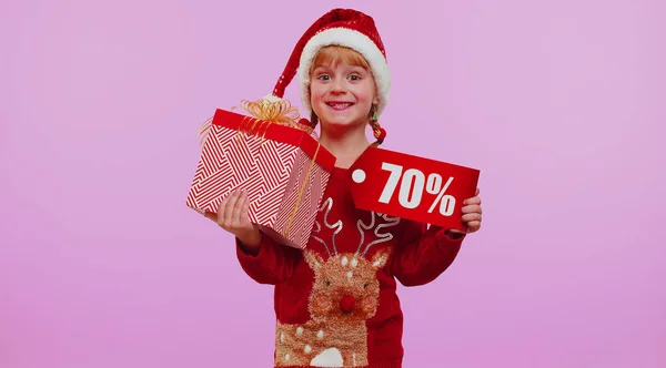 Menina criança em chapéu de Natal vermelho mostrando caixa de presente e 70 por cento de desconto inscrições banner texto nota — Fotografia de Stock