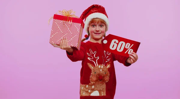 Criança menina em chapéu de Natal mostrando caixas de presente e 60 por cento de desconto inscrições banner texto nota — Fotografia de Stock