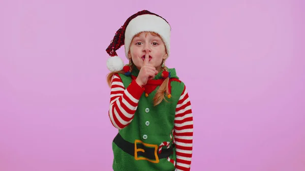 Menina criança em traje de Elfo de Natal pressiona dedo indicador para lábios faz sinal de gesto de silêncio, segredo — Fotografia de Stock
